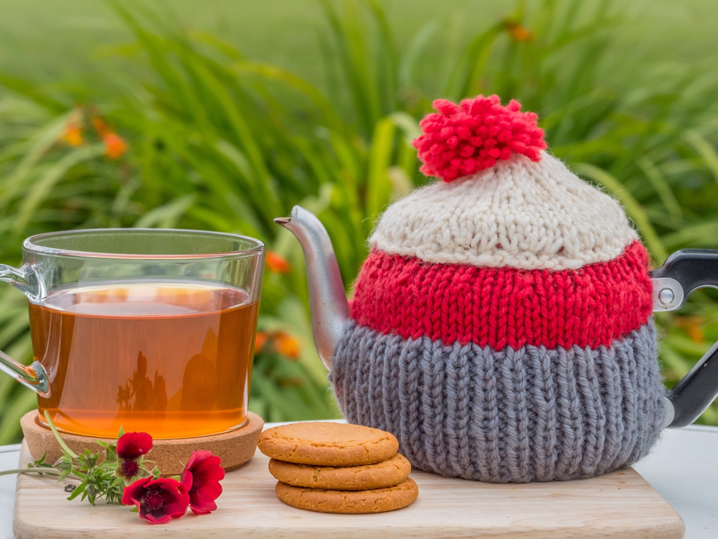 Чайник с чашкой чая на столе с печеньем и цветами