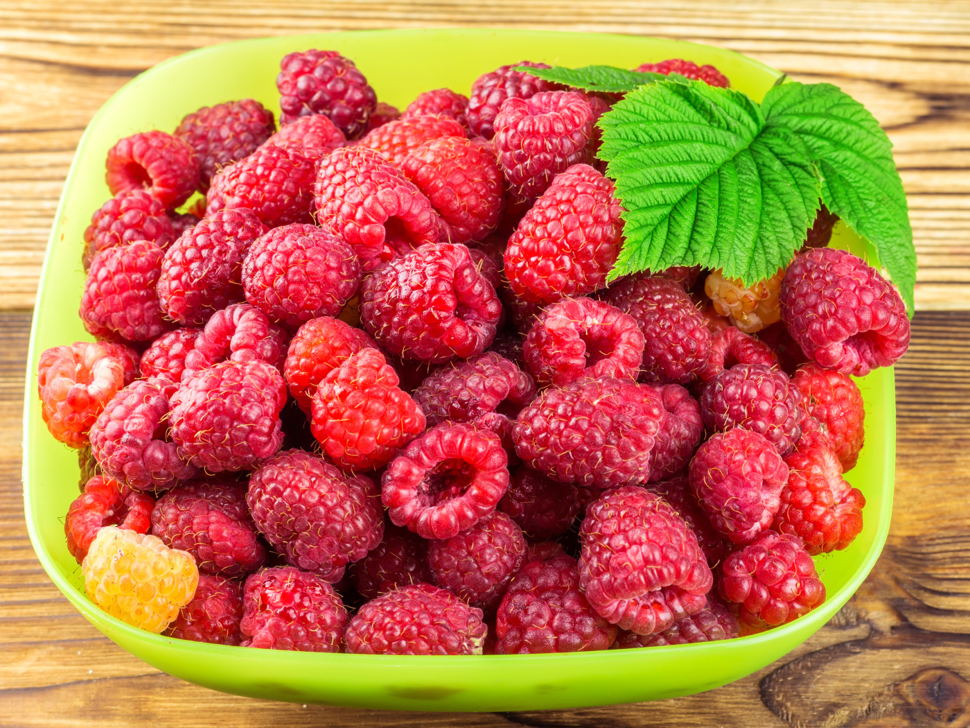 Свежая малина в зеленой миске на столе