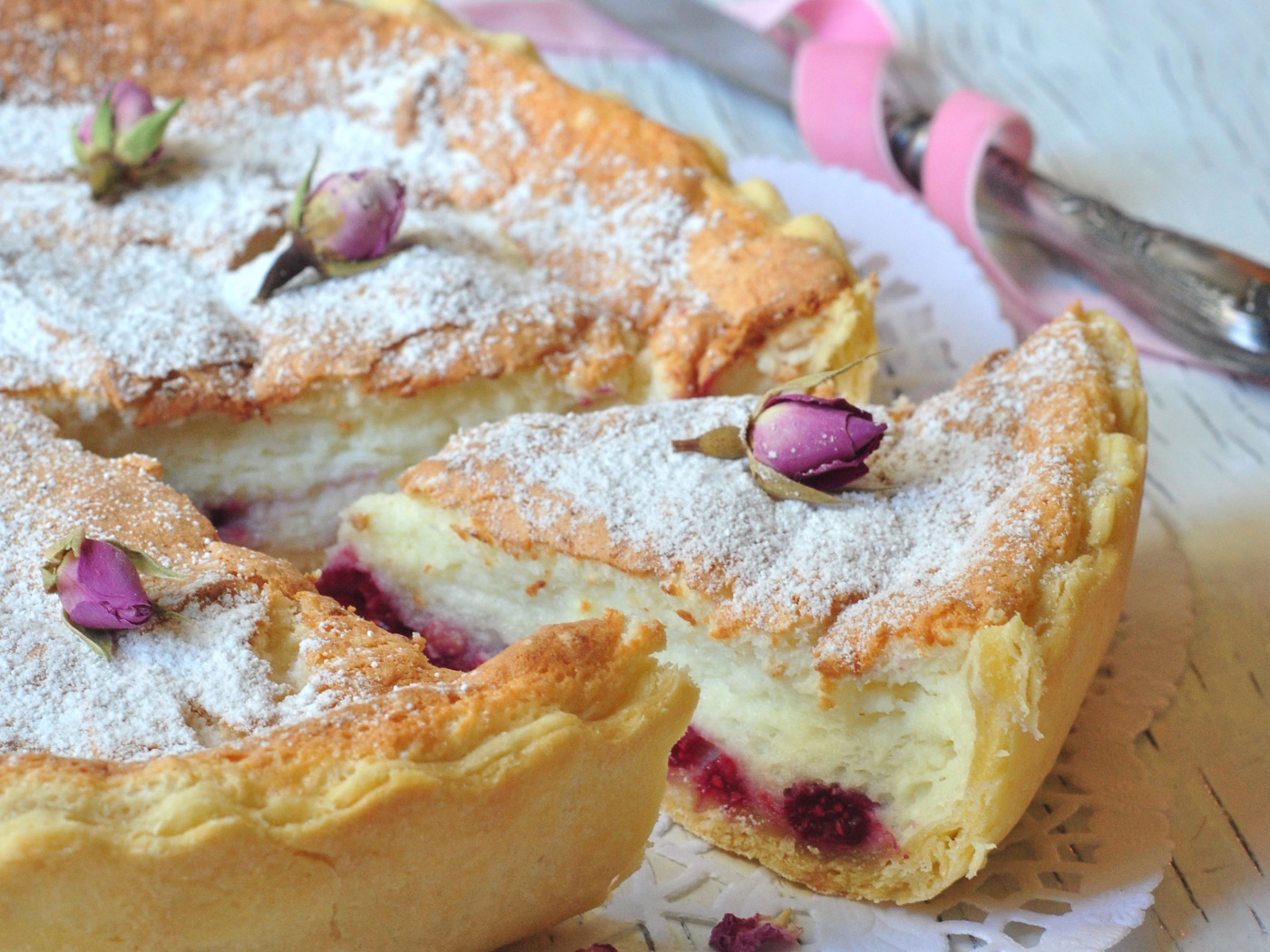 Пирог с суфле и малиной посыпанный сахарной пудрой и цветами