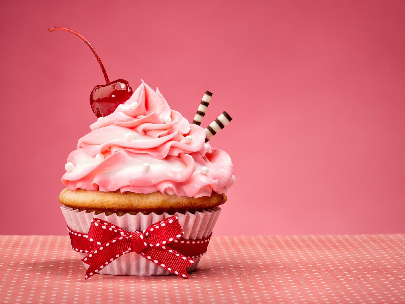 Капкейк с кремом и вишней красиво украшен лентой