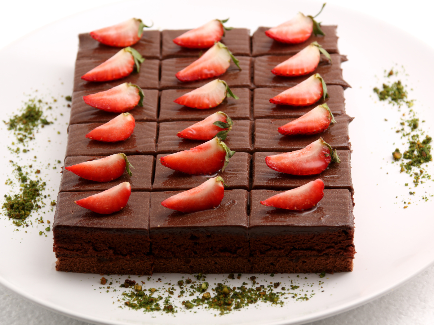 Шоколадное пирожное со свежей клубникой на белой тарелке