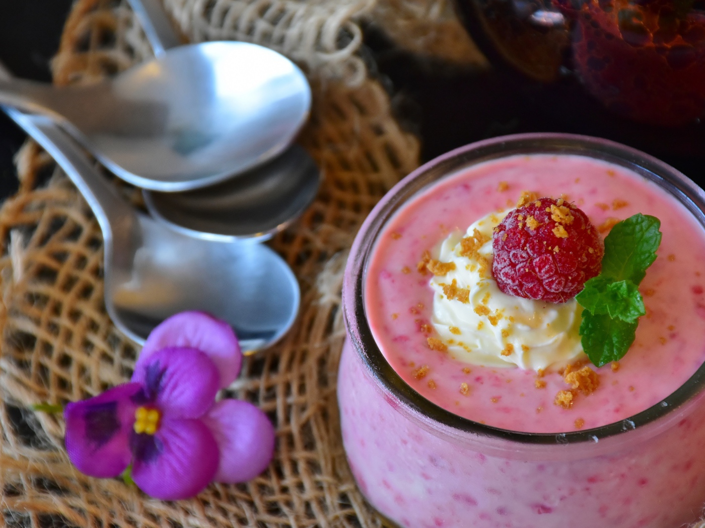 Десерт с малиной и кремом на столе с ложками