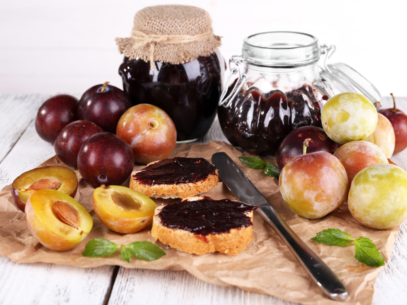 Свежие сливы и сливовый джем на столе 