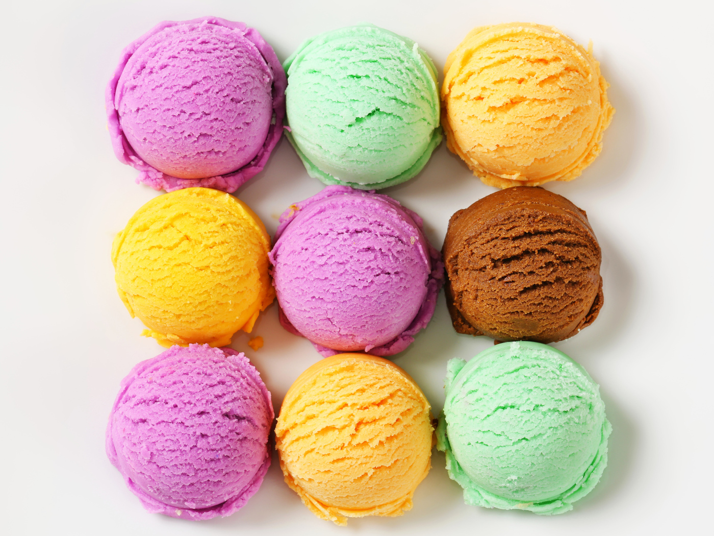 Разноцветные аппетитные шарики мороженого на белом фоне