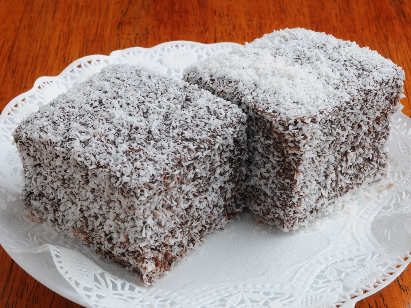 Два кусочка пирожного в кокосовой стружке на белой тарелке