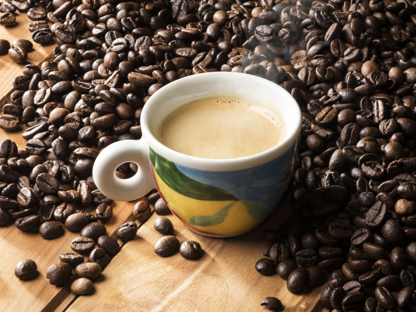 Чашка горячего кофе с кофейными зернами на столе