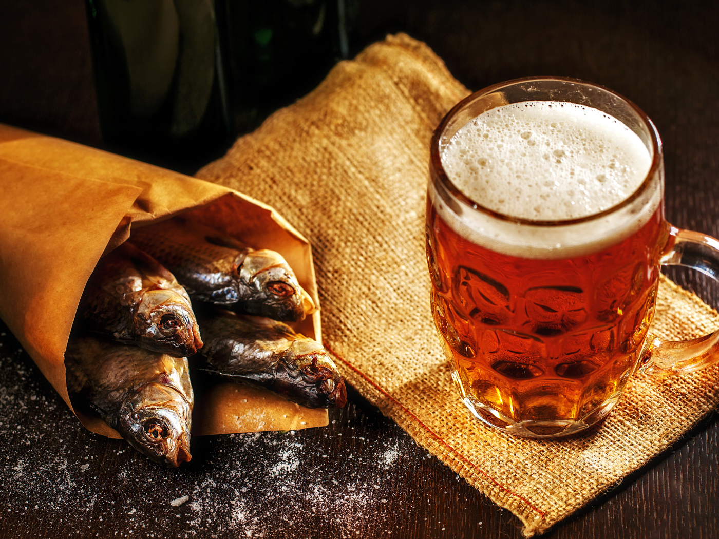 Бокал пива с сушеной рыбой на столе
