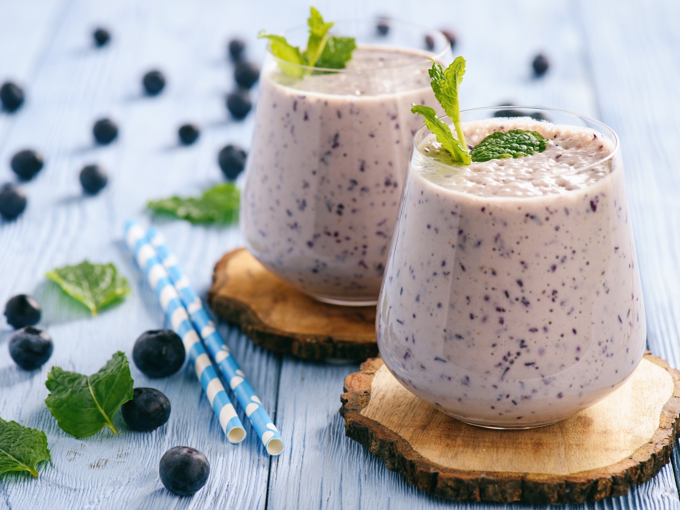 Черничный смузи на столе со свежими ягодами и трубочками