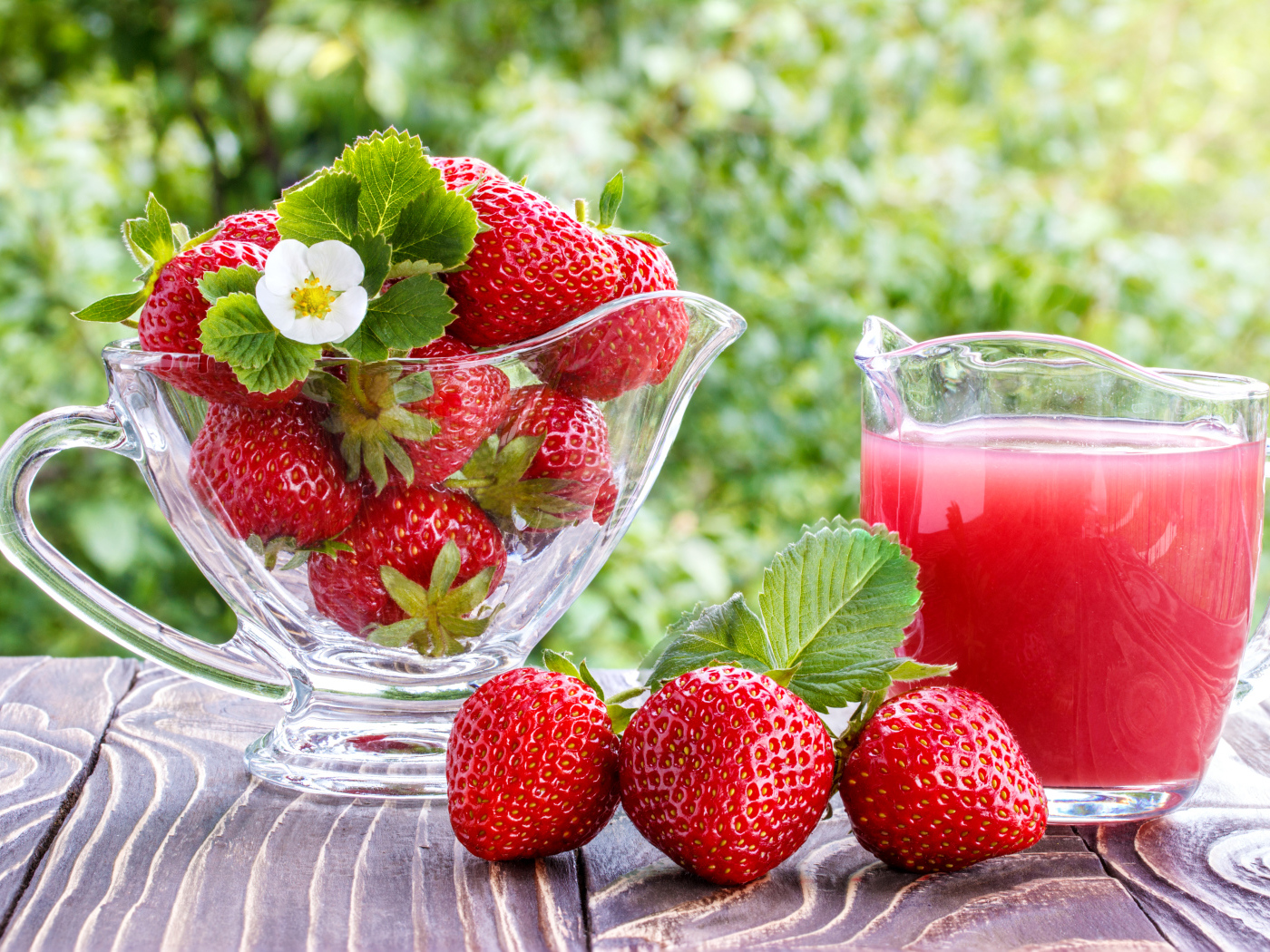 Клубничный сок в стеклянном графине на столе со свежей клубникой