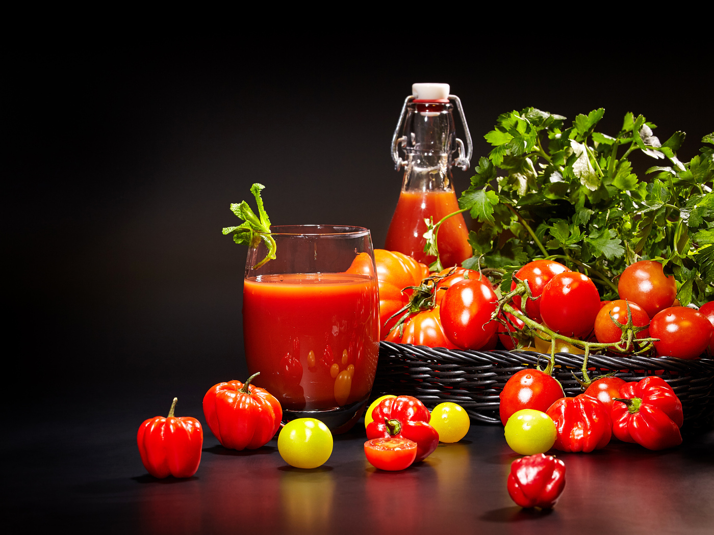 Томатный сок и свежие помидоры на столе на черном фоне