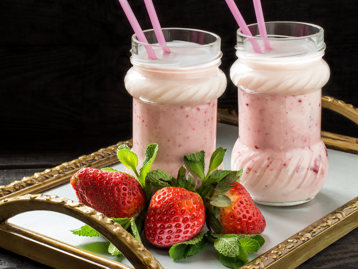 Два свежих клубничных коктейля с трубочками и ягодами клубники