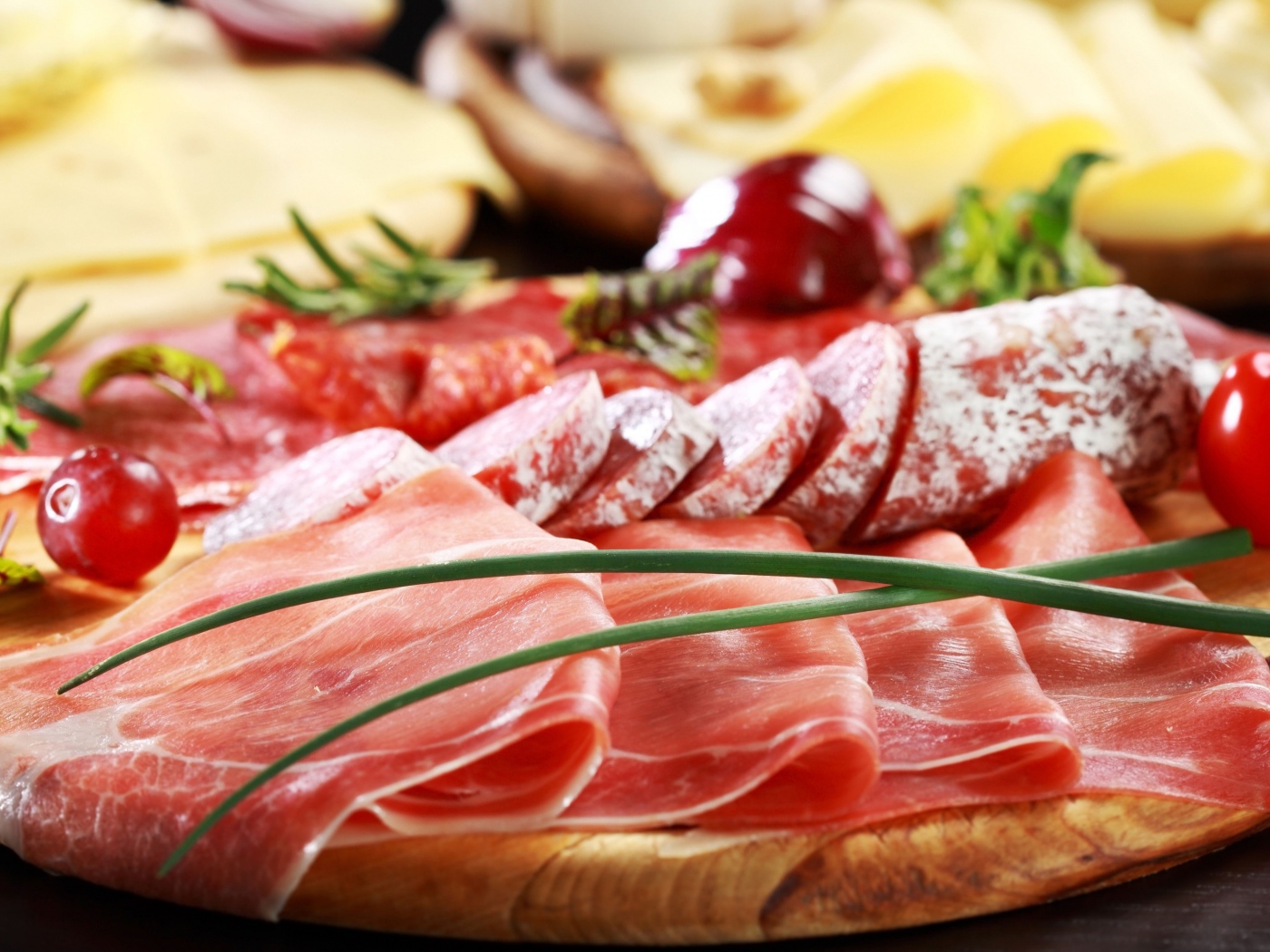 Мясная нарезка на разделочной доске с овощами