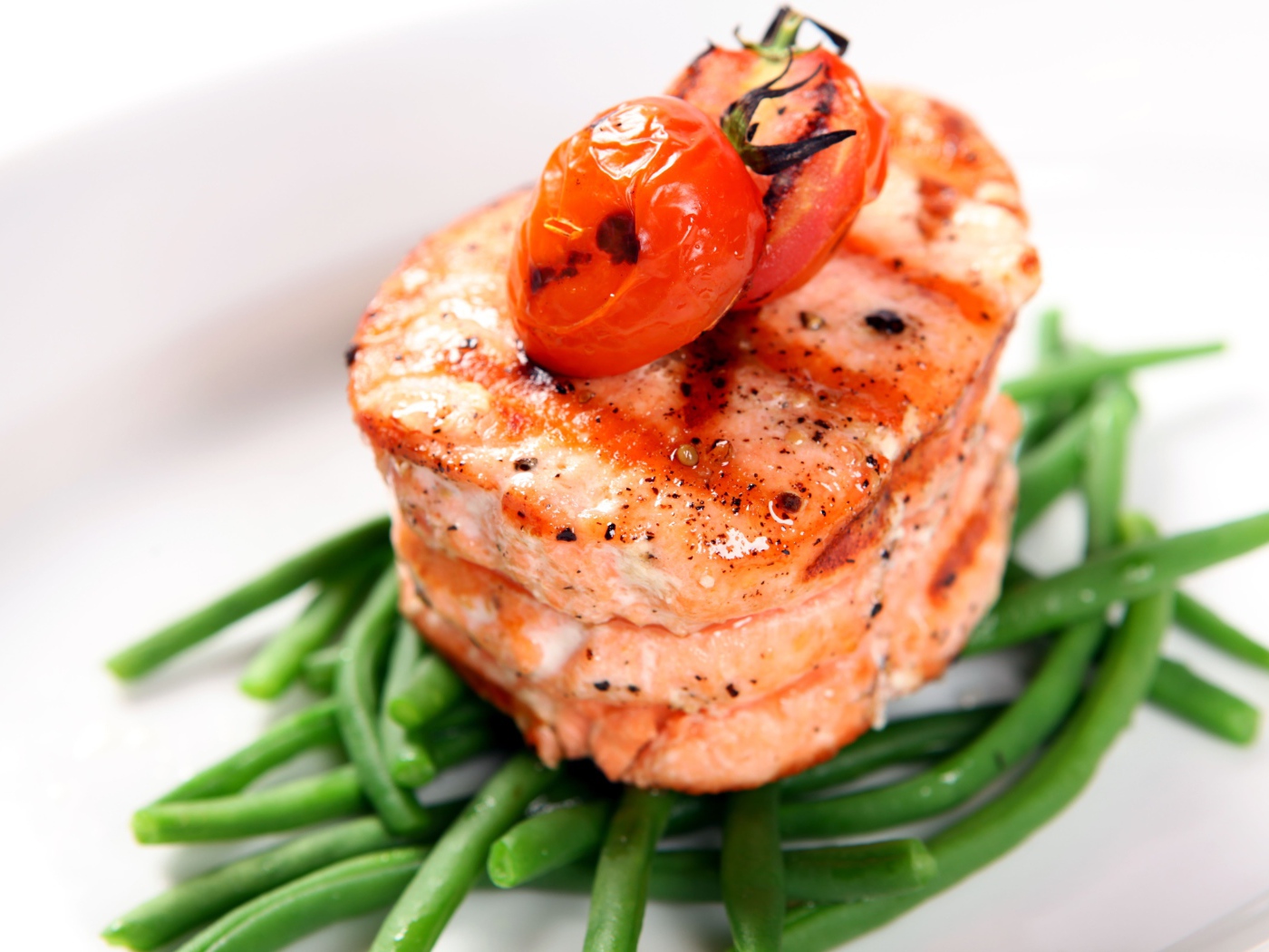 Кусок запеченной рыбы на тарелке с помидорами