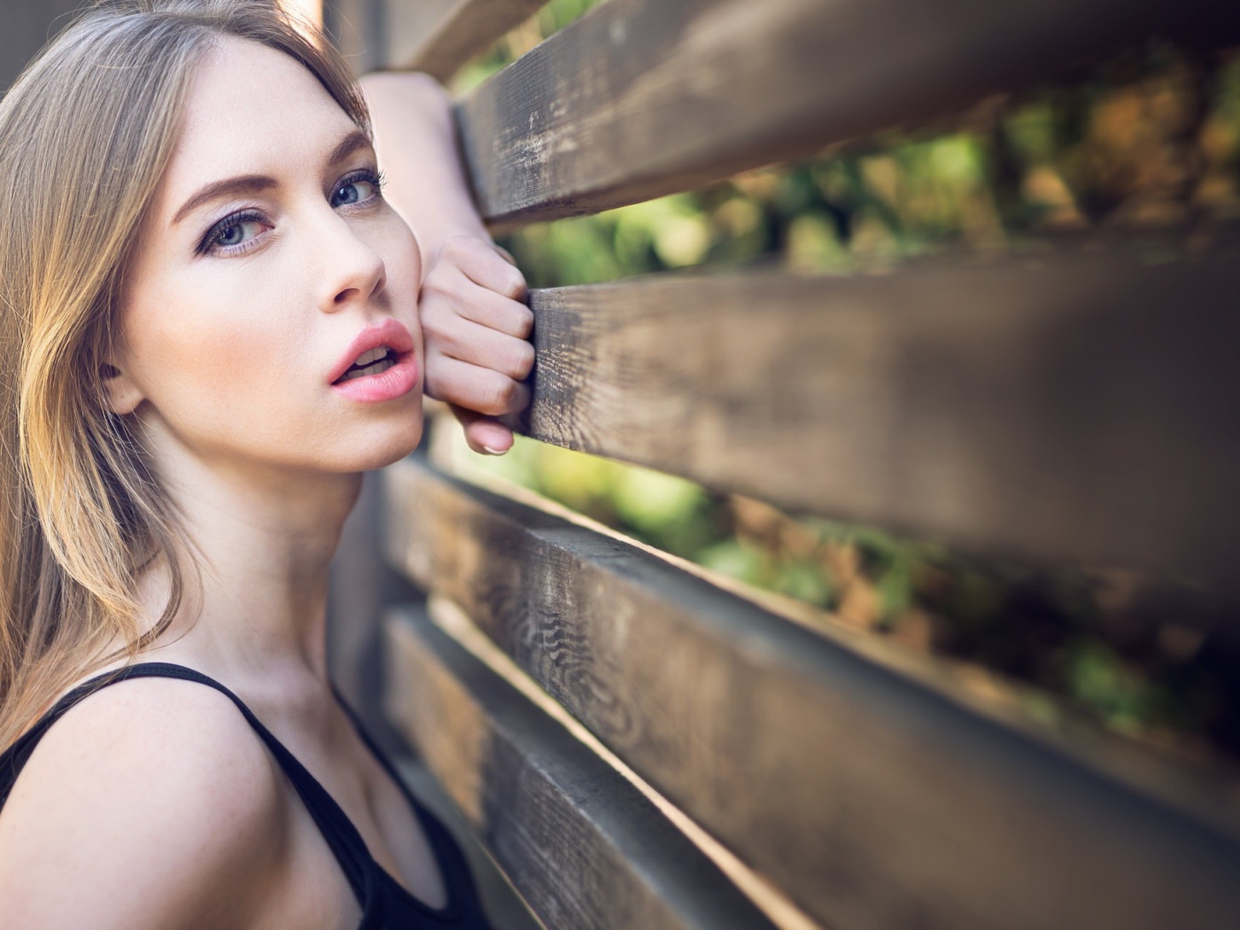 Красивая голубоглазая девушка у деревянного забора 
