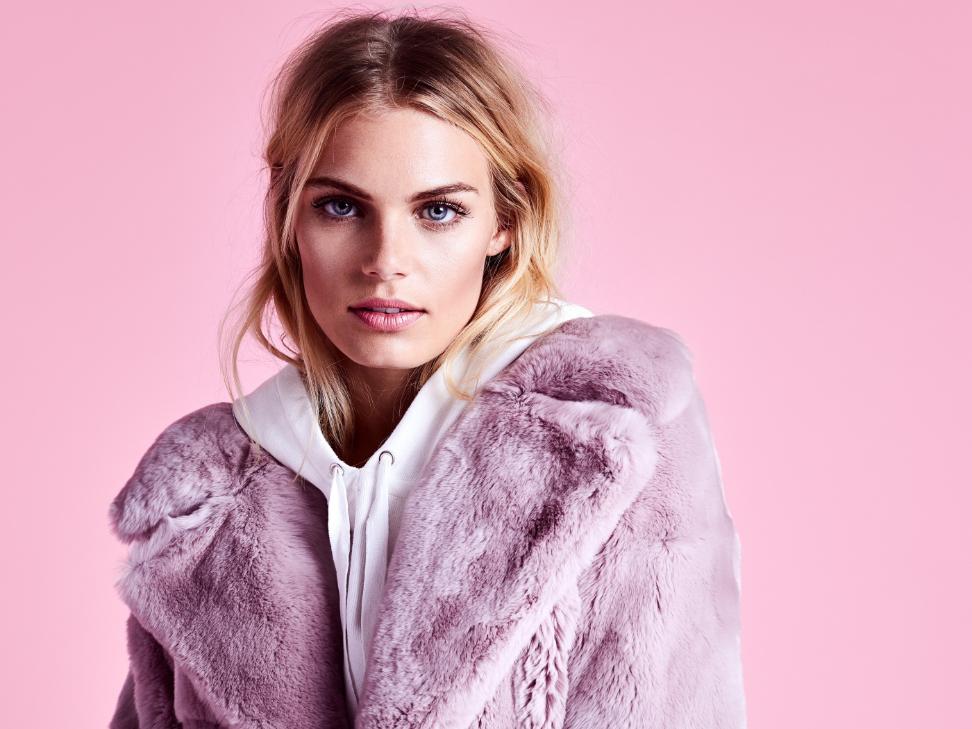 Красивая голубоглазая девушка в шубе на розовом фоне