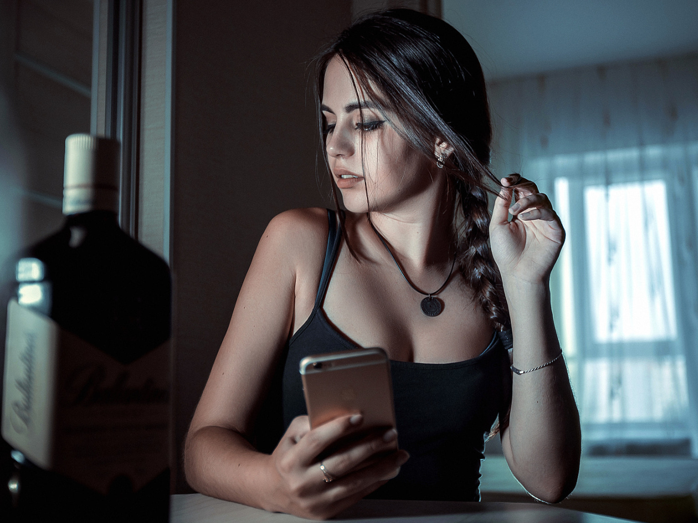 Красивая брюнетка с телефоном в руках и бутылкой