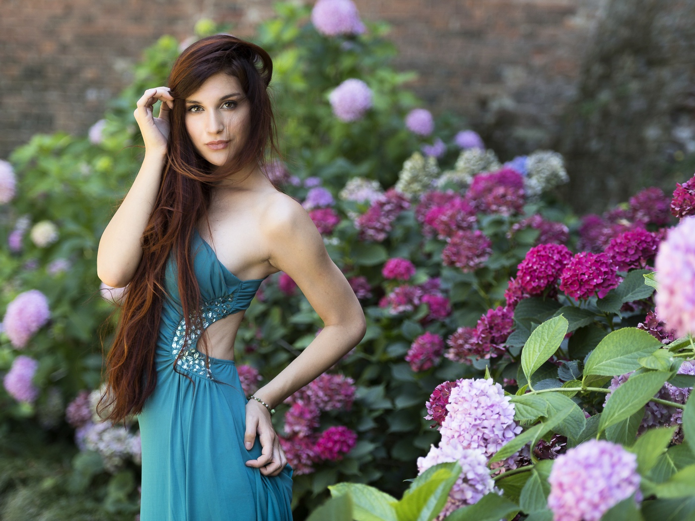 Красивая девушка модель в зеленом платье рядом с цветами гортензии