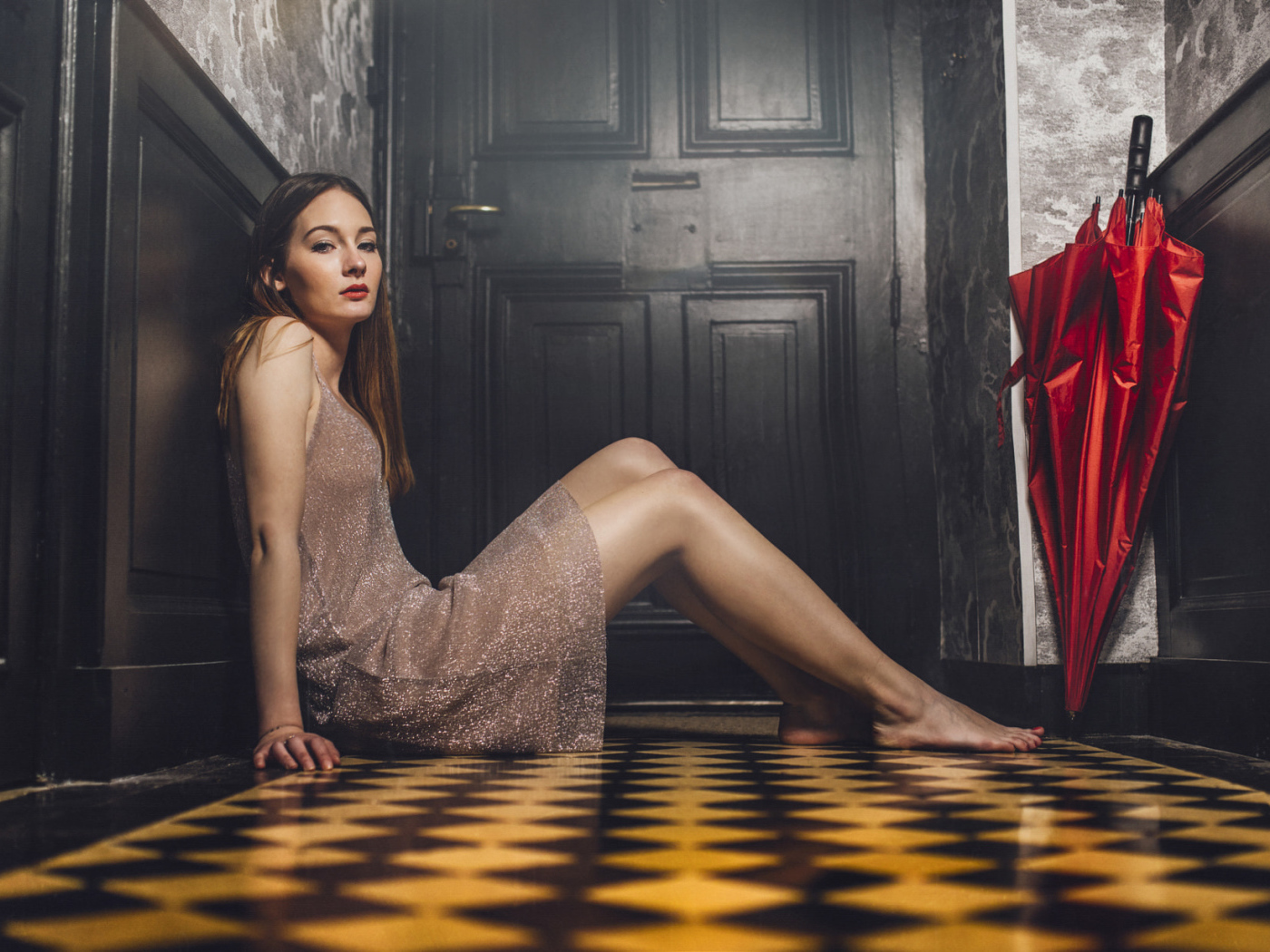 Красивая девушка модель с красным зонтом сидит на полу