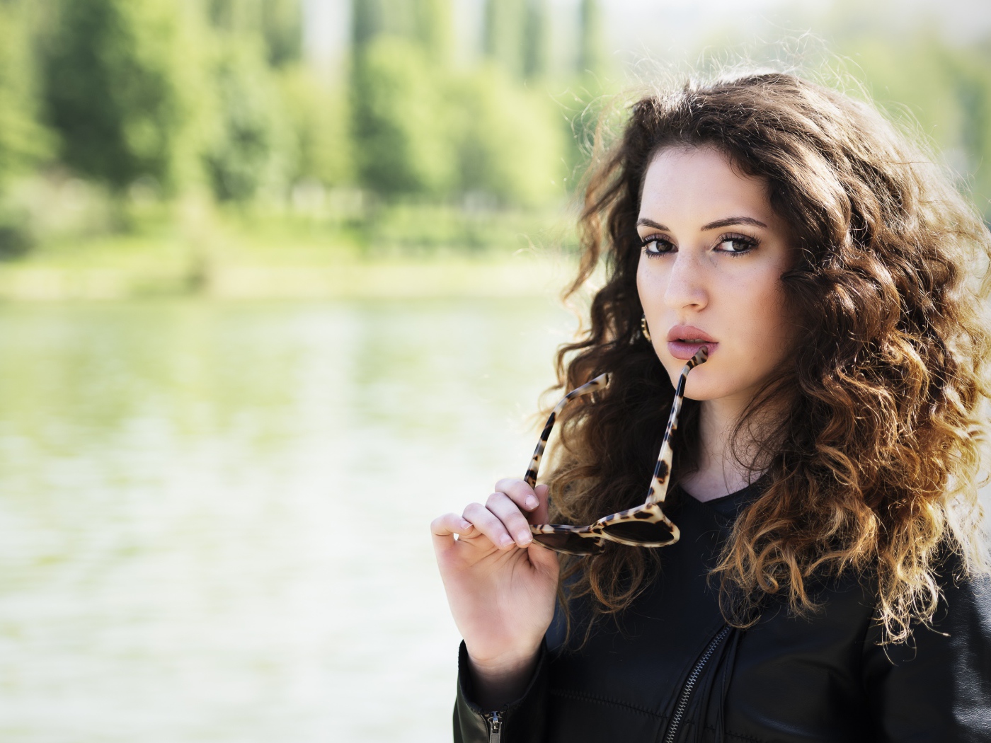 Красивая девушка с волнистыми волосами с очками в руках 