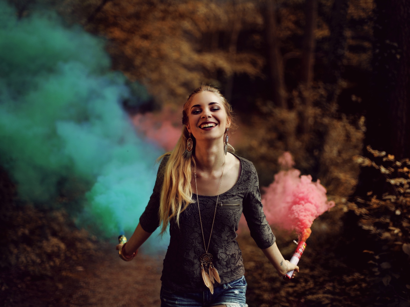 Красивая улыбающаяся девушка с дымовыми шашками в руках