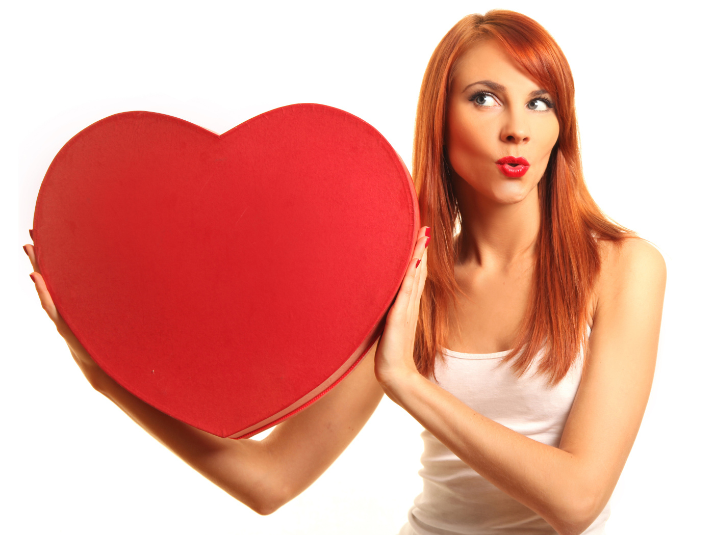 Рыжеволосая девушка с большим красным сердцем в руках на белом фоне