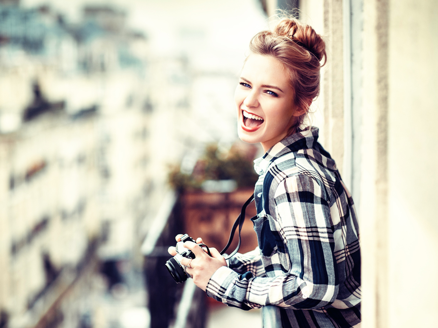 Улыбающаяся девушка в клетчатой рубашке с фотоаппаратом 