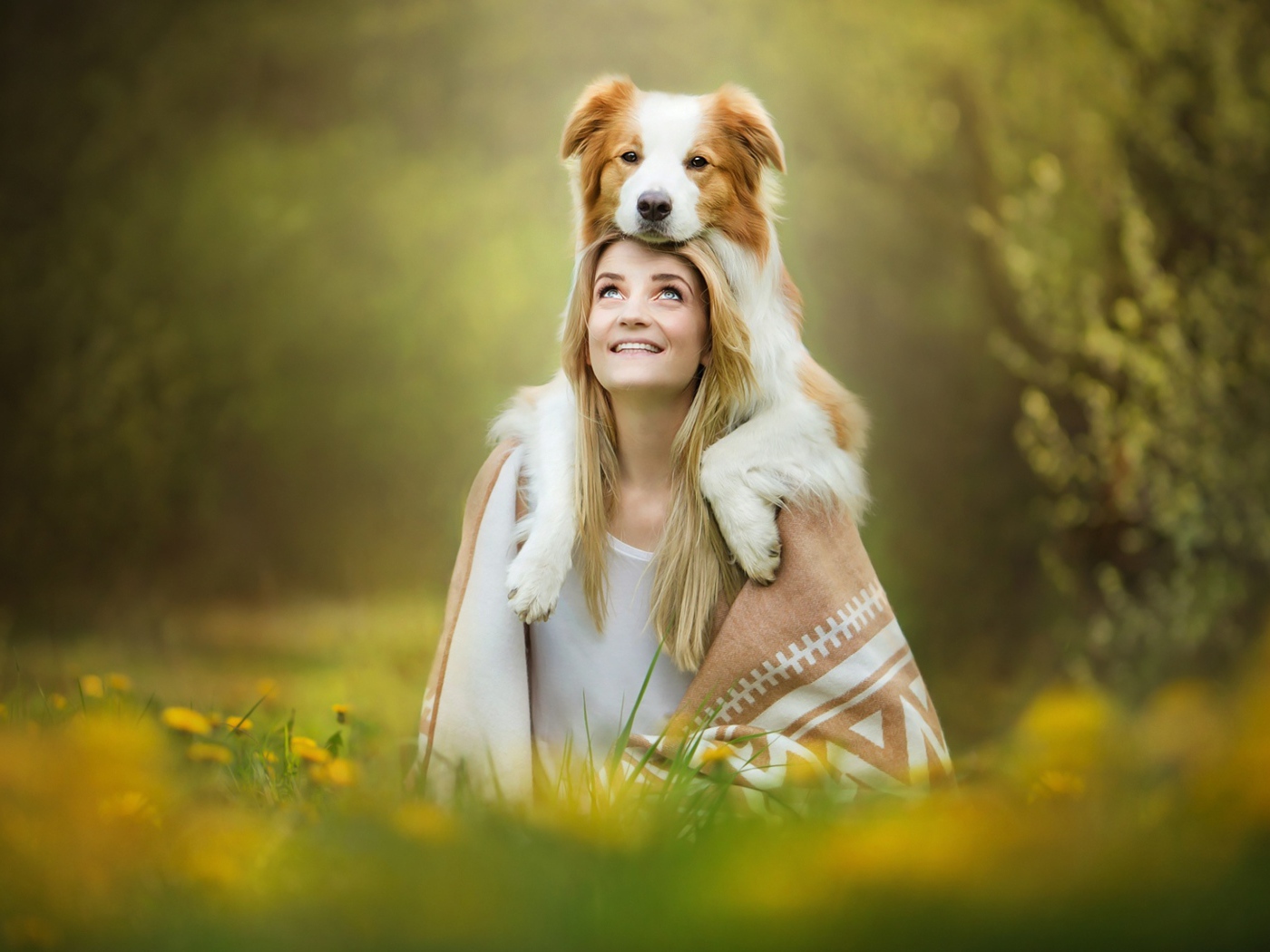 Улыбающаяся девушка с собакой сидят на траве