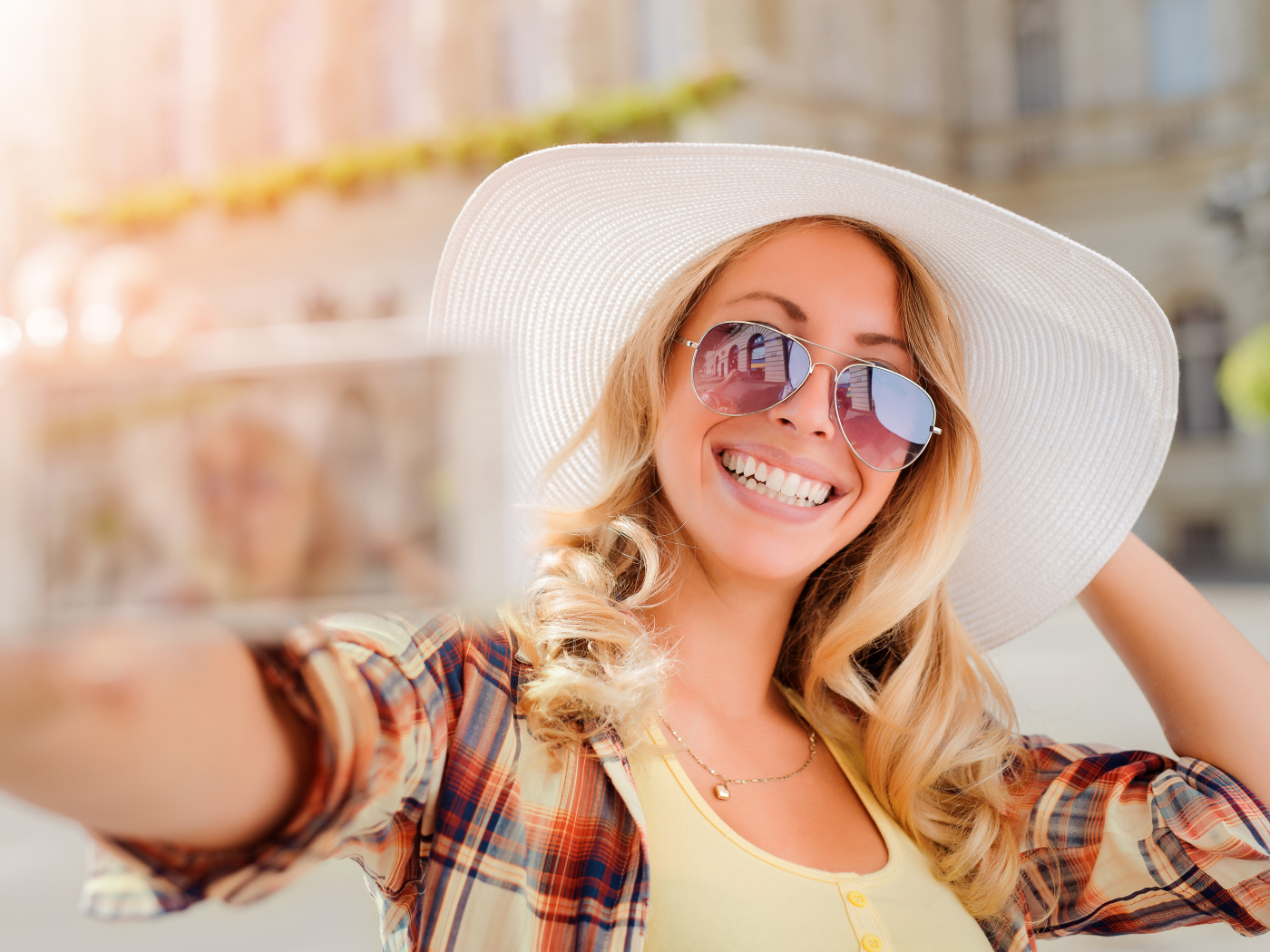 Улыбающаяся девушка в очках и большой белой шляпе 