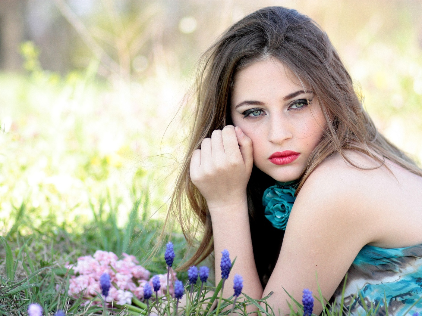 Молодая девушка брюнетка с голубыми глазами лежит на траве 