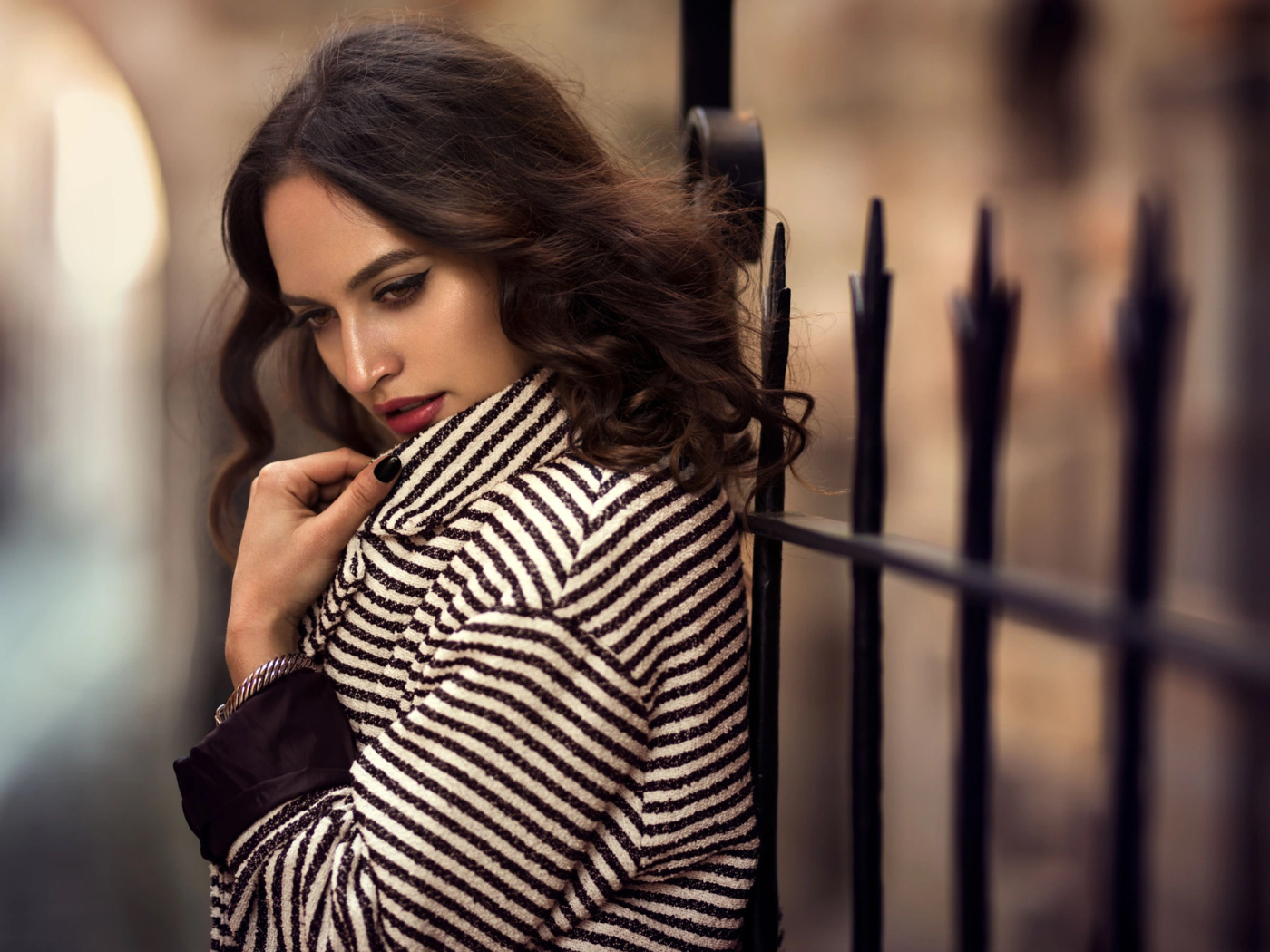 Молодая брюнетка в пальто у забора