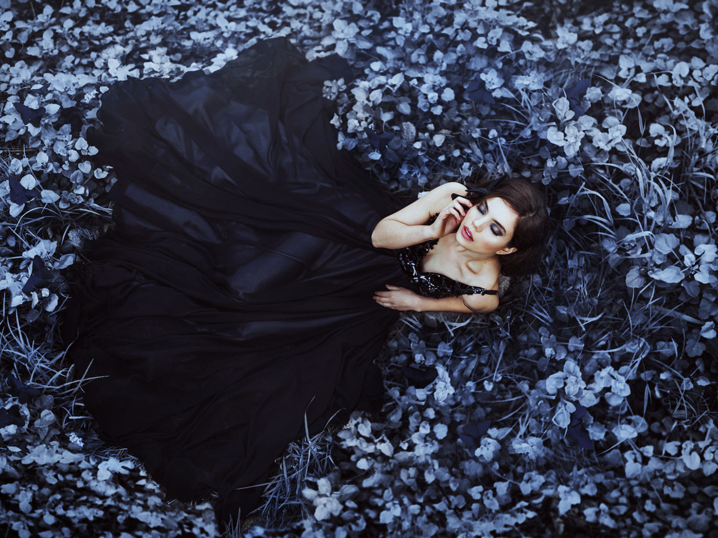 Молодая девушка модель с красивом черном платье лежит на траве