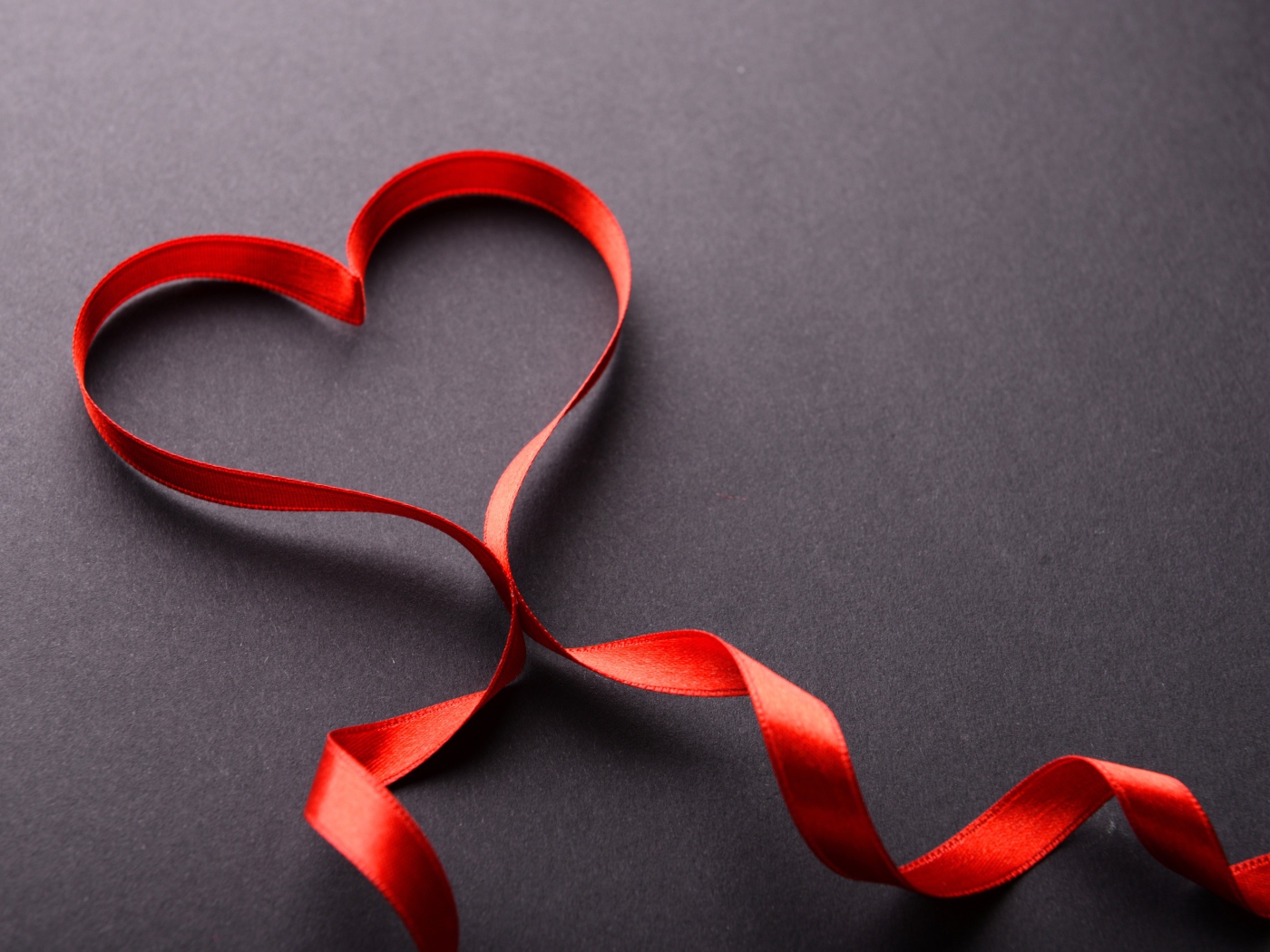 Красное сердце из атласной ленты на сером фоне