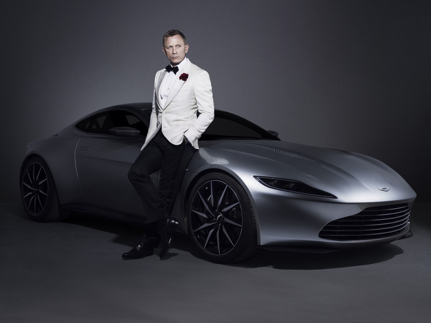 Знаменитый актер Дэниел Крэйг рядом с серебристым автомобилем Aston Martin
