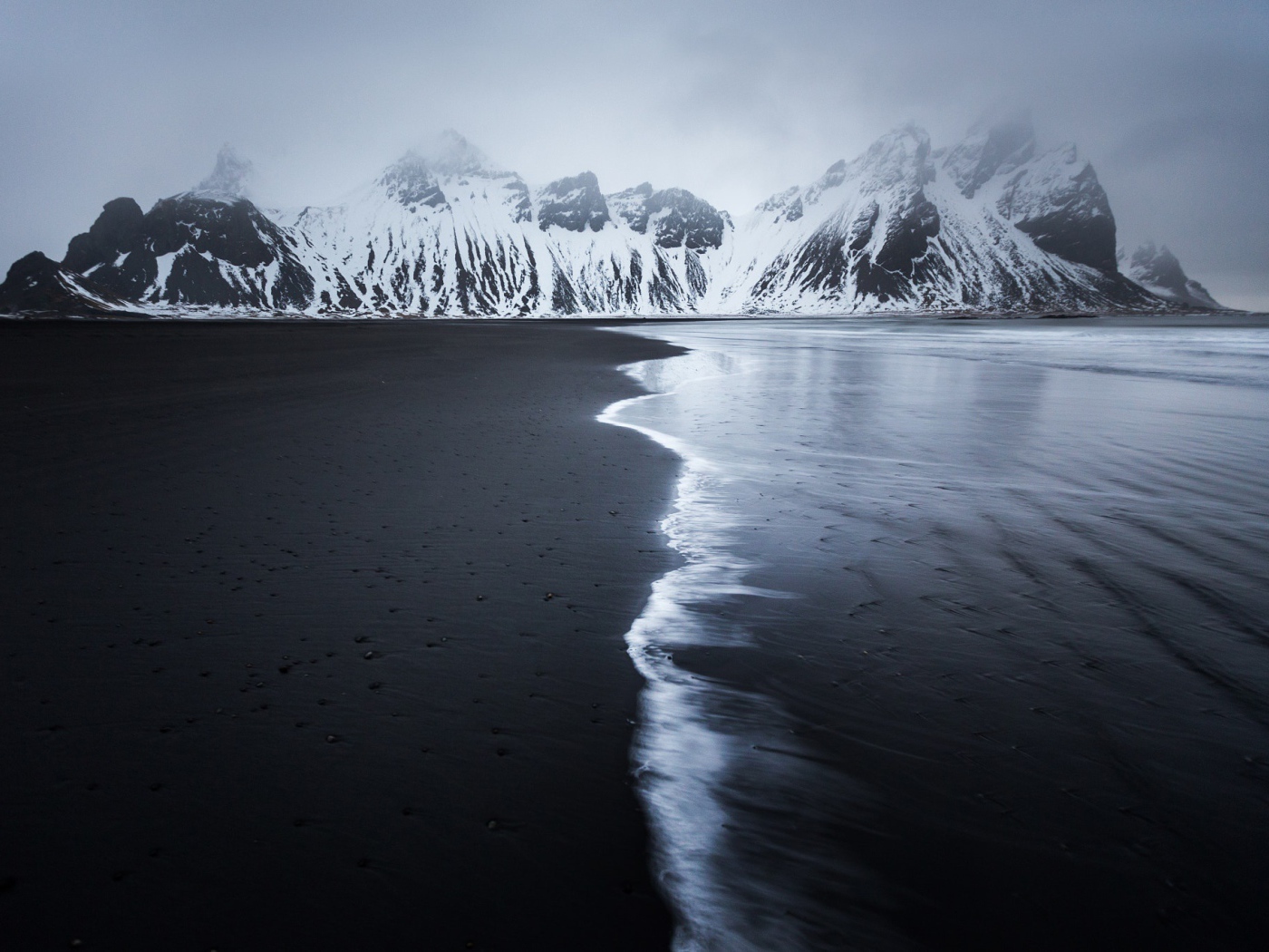 Заснеженные горы у пустынного пляжа