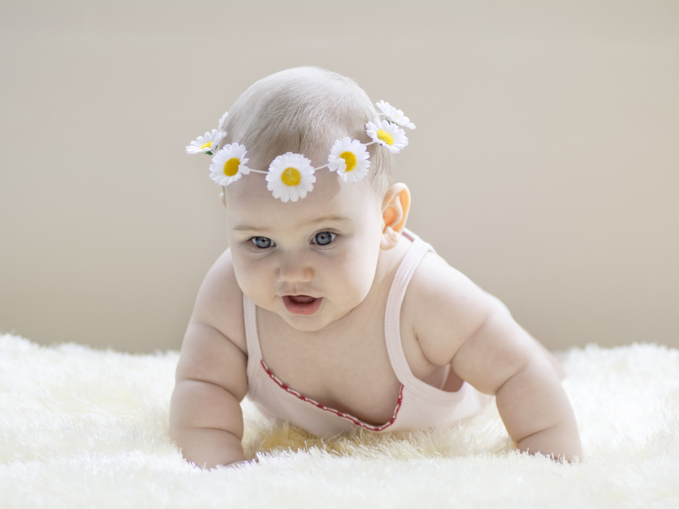 Грудной ребенок с венком из белых ромашек на голове