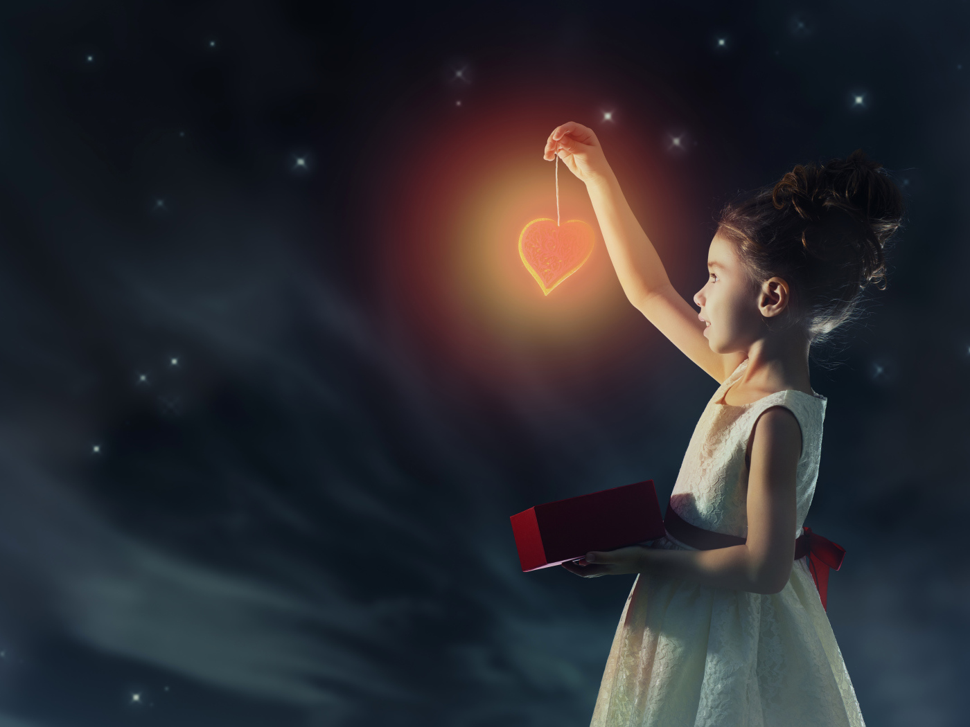 Девочка в красивом белом платье держит в руках сердечко