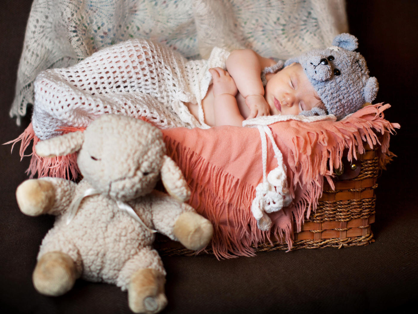 Спящий грудной ребенок в забавной шапке с мягкой игрушкой