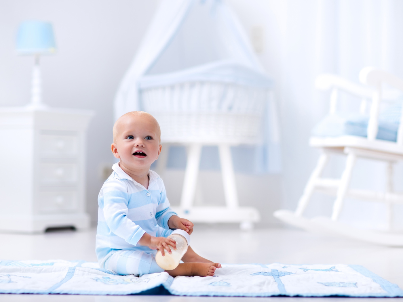 Маленький голубоглазый мальчик сидит на полу в комнате