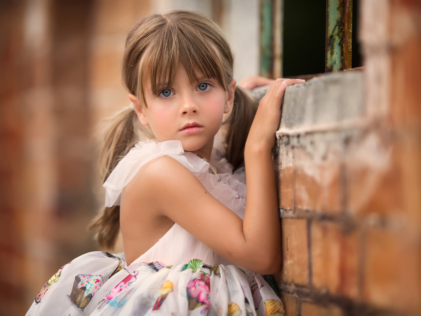 Милая девочка с серьезным взглядом стоит у стены
