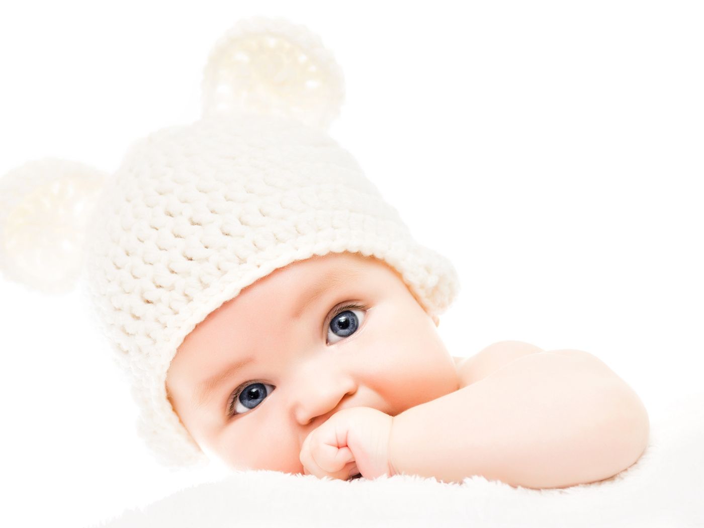 Голубоглазый младенец с белой шапке с ушками на белом фоне