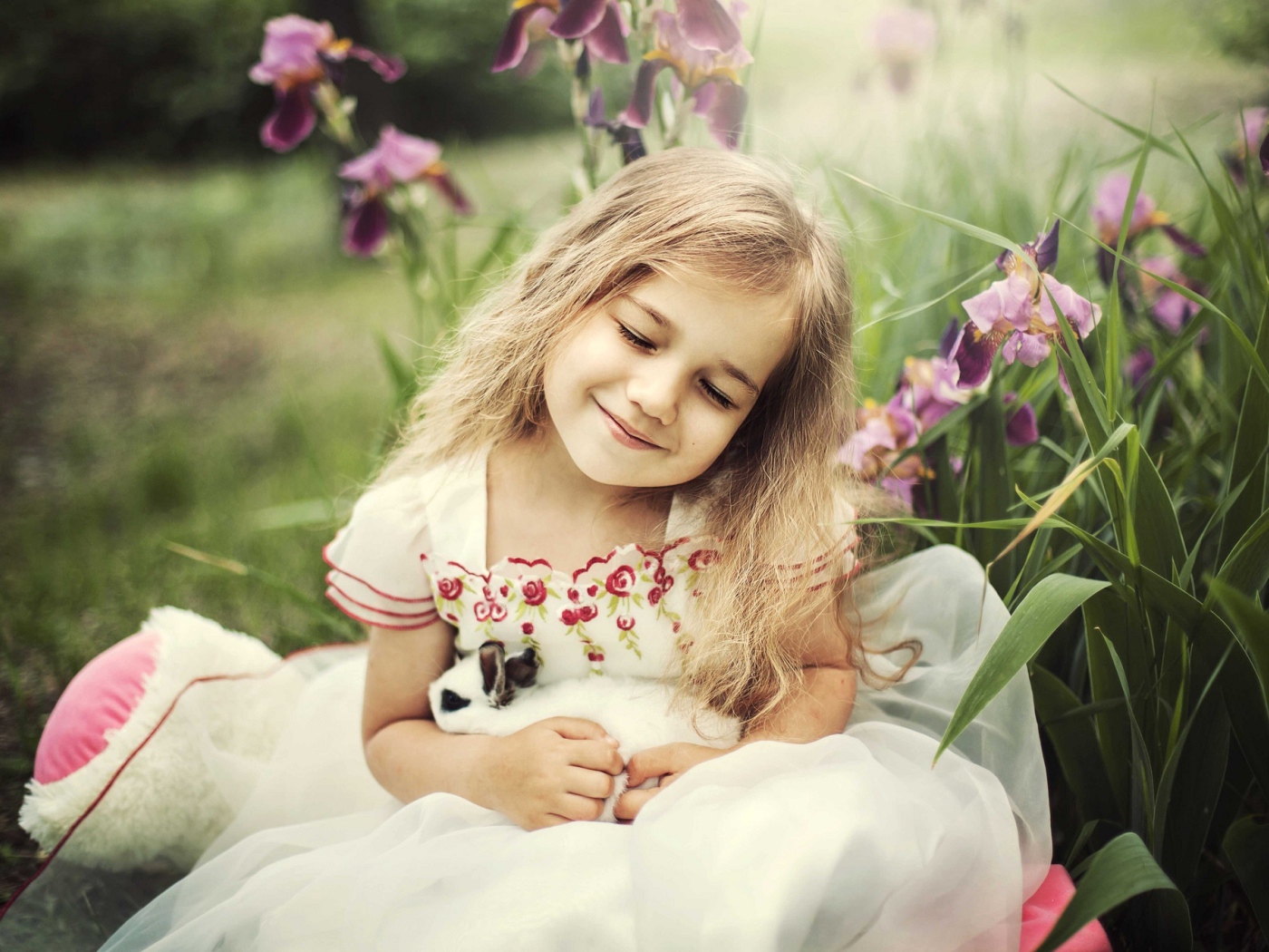 Маленькая девочка блондинка держит в руках кролика