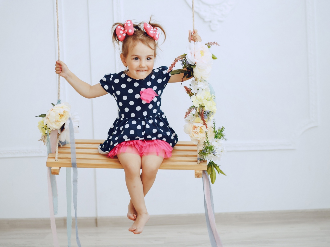 Маленькая забавная девочка в платье в горох  на качели