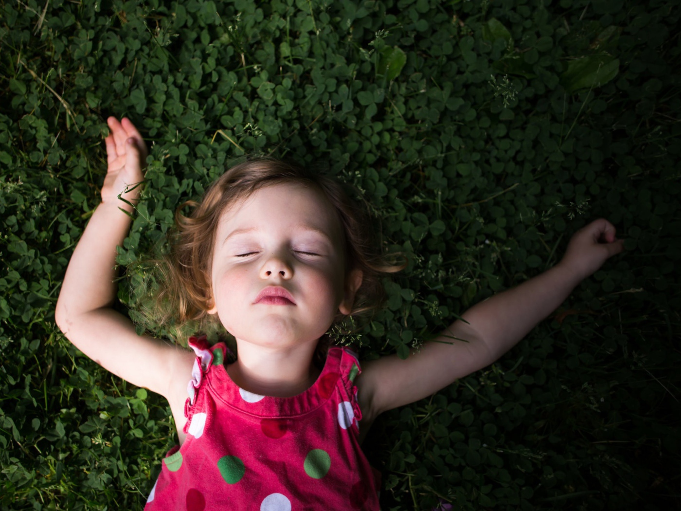 Маленькая девочка спит на зеленой траве 