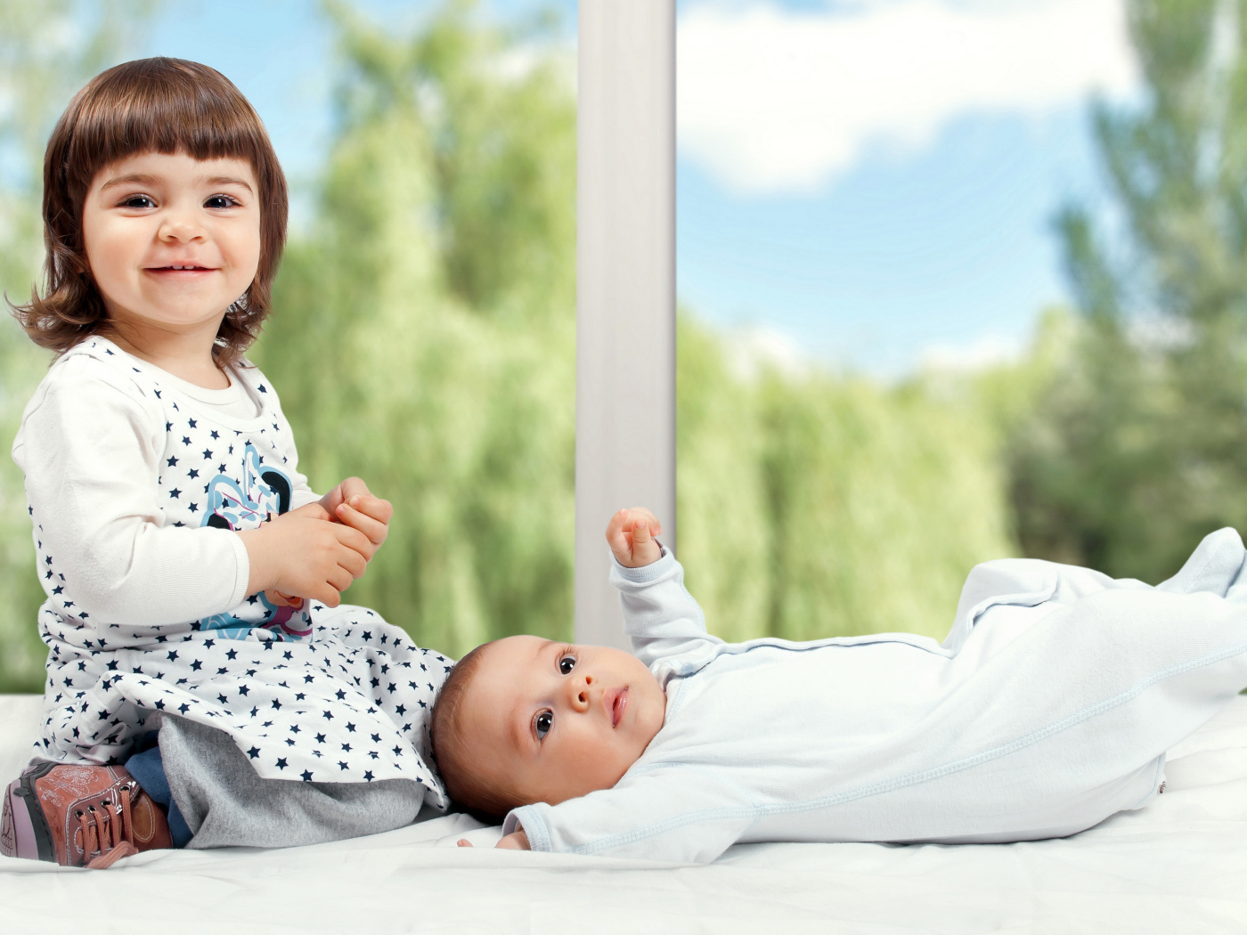 Маленькая улыбающаяся девочка с грудным ребенком