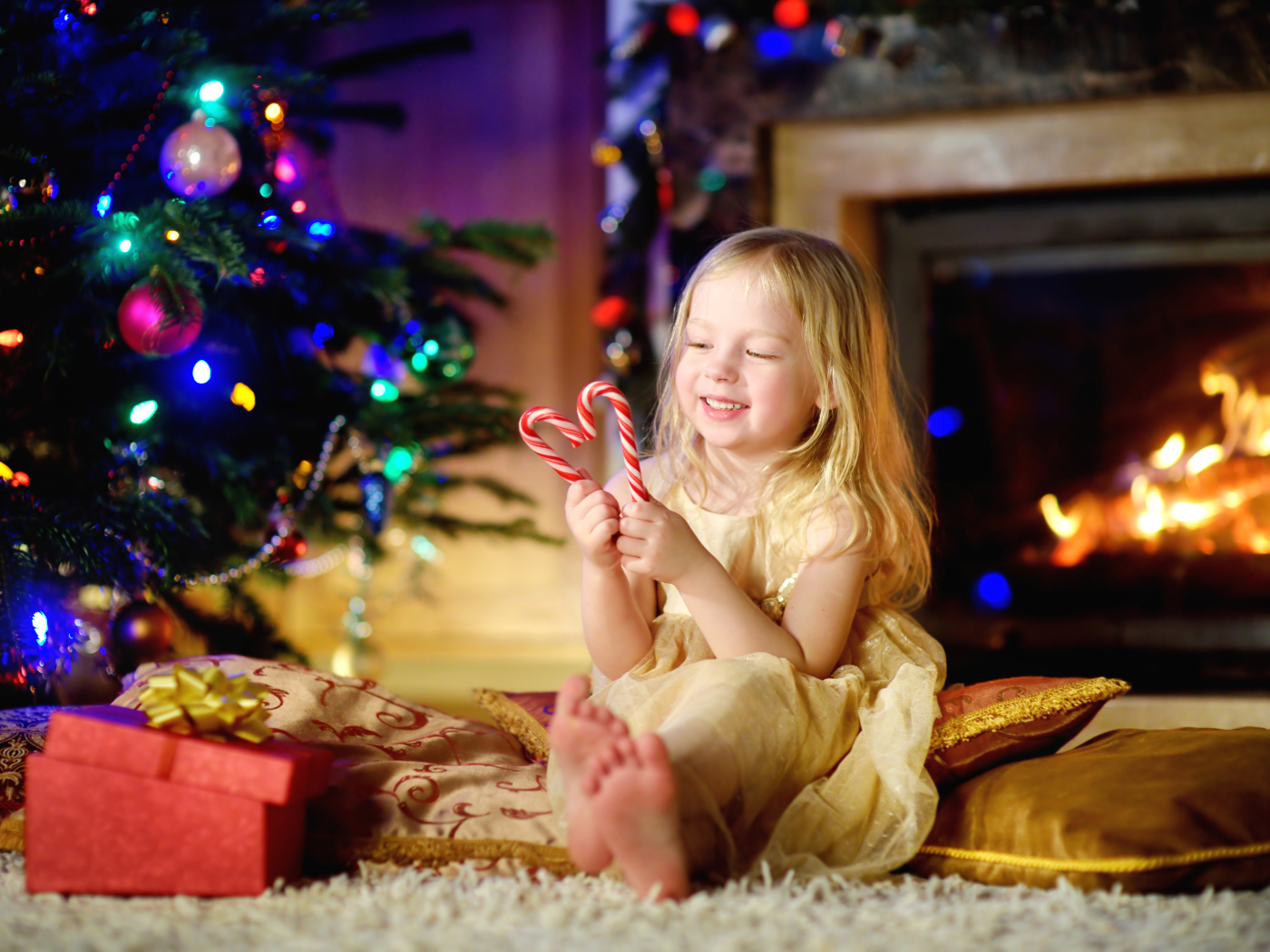 Длинноволосая девочка блондинка с леденцами у новогодней елки