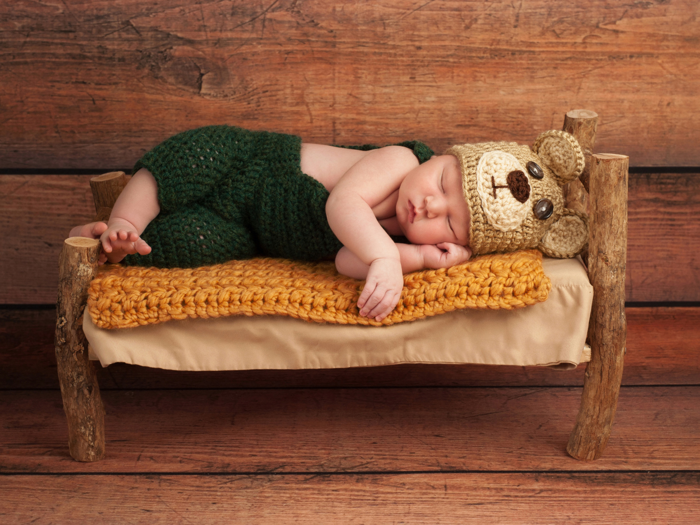 Новорожденный ребенок в костюме медвежонка спит на крошечной кровати