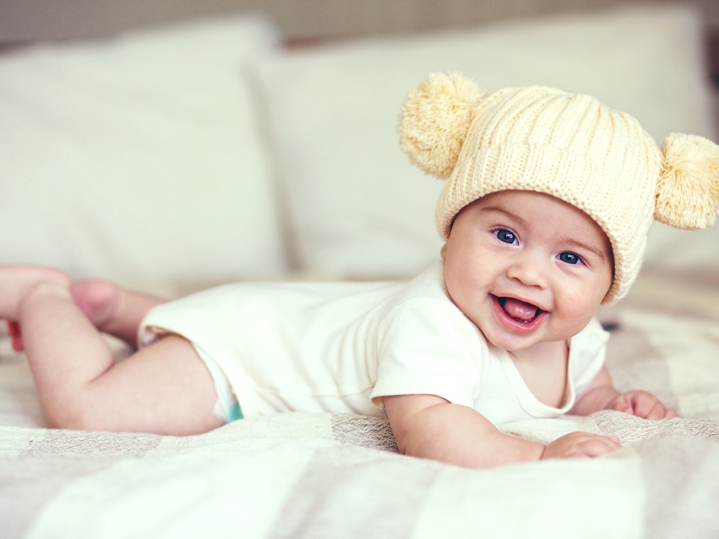 Улыбающийся грудной ребенок в забавной вязаной шапке