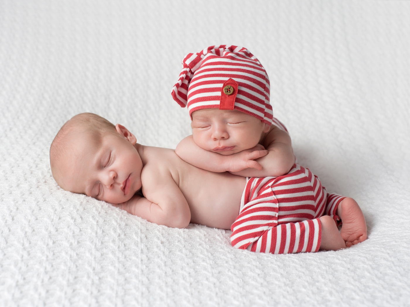 Два милых спящих младенца в полосатых костюмах