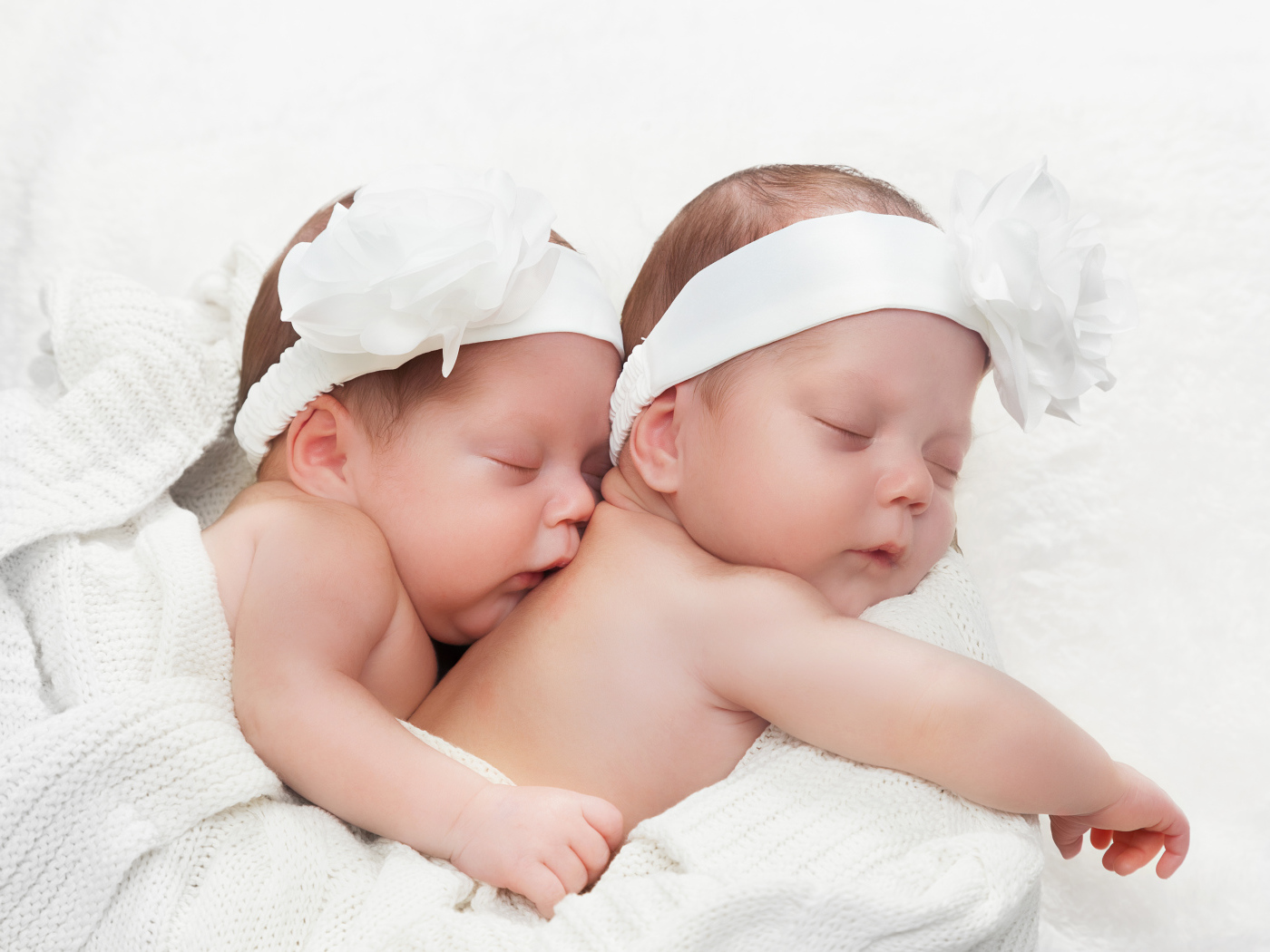 Два спящих младенца с большими белыми цветами на голове