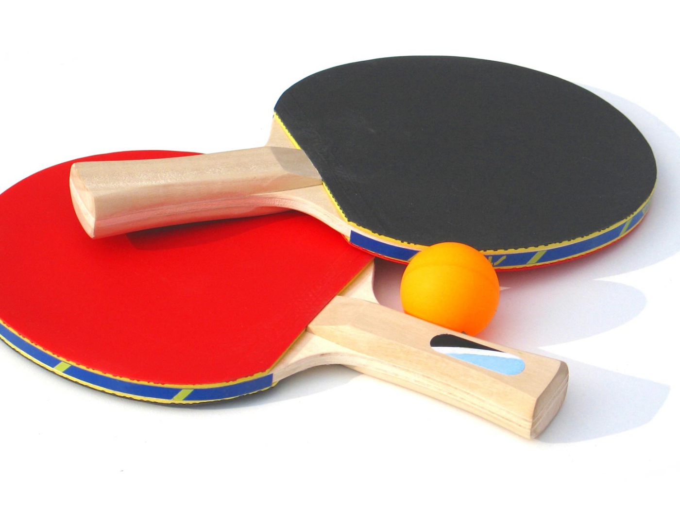 Красная и желтая ракетки и мяч на белом фоне  